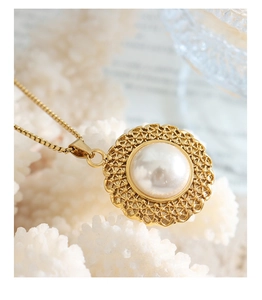 Macro detail of French vintage pearl pendant with intricate lace metal gold weaving