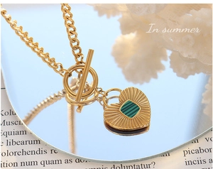 Detail of OT buckle closure and heart pendant with green striped inlay on a gold chain