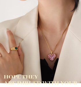 Nahaufnahme der rosa Herz-Zirkon-Halskette und des grünen Edelsteinrings am Modell
