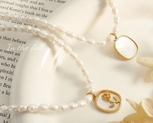 Détail d'un collier de perles baroques avec pendentif rose en nacre sur une assiette blanche