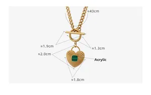 Detail view of gold heart pendant with green acrylic inlay and decorative OT toggle clasp