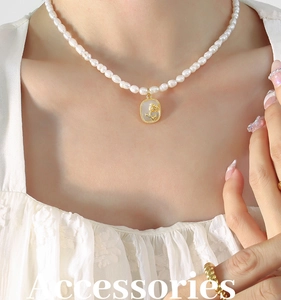 Détail du collier de perles baroques avec pendentif rose dorée en relief et zircons