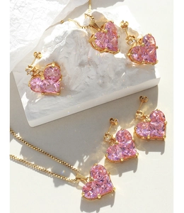 Nahaufnahme des rosa herzförmigen Kristall-Schmucksets auf elegantem weißem Stein