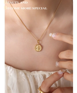 Gros plan du collier en or avec pendentif reine en relief porté sur un chemisier blanc