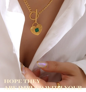 Detail of vintage heart pendant with green acrylic inlay and gold toggle clasp