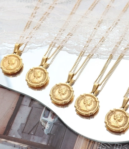 Cinq colliers avec pendentif pièce Elizabeth II en relief sur une surface miroir