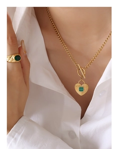 Detail of vintage heart pendant necklace with green acrylic inlay and gold Cuban chain