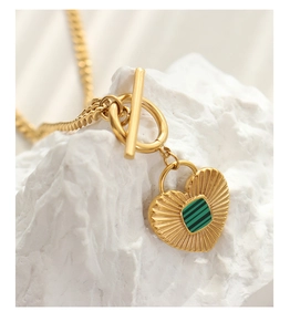 Macro view of gold heart pendant with green striped inlay and stylish toggle clasp