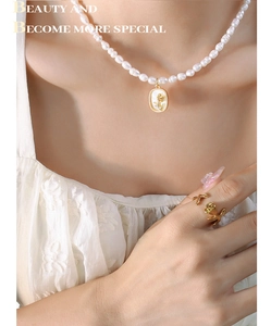 Détail du collier de perles baroques et bague rose dorée sur mannequin pour look élégant