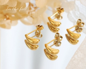 Macro shot of polished gold water drop earrings with reflections on a clean surface
