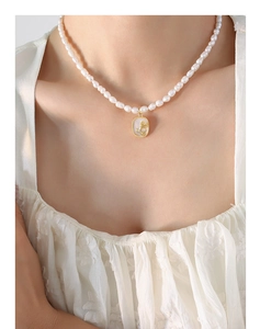 Collier de perles avec pendentif en relief de rose dorée porté par un mannequin chic