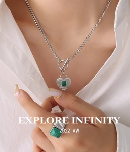 Close-up of OT buckle heart pendant necklace and wavy ring with green malachite inlay