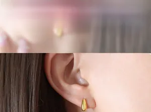 Close-up of minimalist golden waterdrop studs worn on ear showcasing polished finish