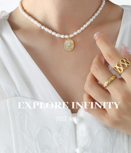 Détail d'un collier de perles baroques avec pendentif rose dorée et bagues assorties