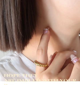 Close-up of golden twist rope ring on finger showing spiral texture and glossy finish
