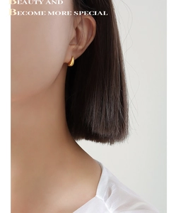Close-up of minimalist gold teardrop stud earrings worn on a female model's ear