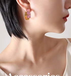 Detail of C-shaped gold-plated earrings with rectangular pink zircon stones on model