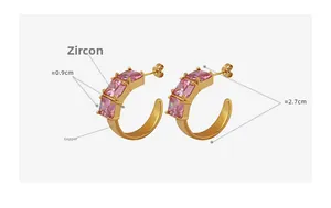 Detail view of gold C-shape earrings with pink square zircons and 2.7cm diameter
