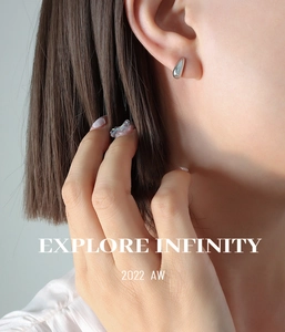 Close-up of minimalist silver teardrop stud earrings worn on ear with polished finish