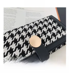 Détail de la texture en tissu pied-de-poule avec fermoir rond en métal doré élégant