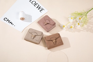 Tre portafogli compatti in pelle opaca viola, taupe e caramello con fibbie metalliche