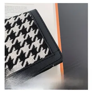 Gros plan sur la texture pied-de-poule et les bords en cuir avec coutures précises