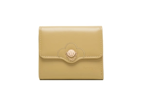 Detail of a mustard yellow tri-fold wallet with flower metal buckle and leather texture
