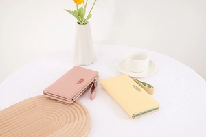 Close-up of pink and yellow PU leather long wallets with wrist straps and metal letters