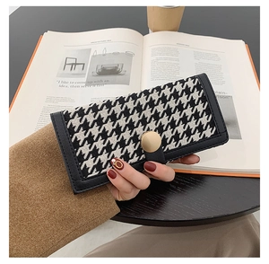 Détail du portefeuille pied-de-poule avec boucle dorée et bordure en cuir noir chic