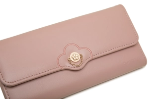 Detail of a pink long wallet featuring a metal flower clasp and floral embroidery