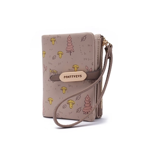 Detail of forest theme short wallet with mushroom prints and a brand metal plate