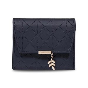 Detail of navy blue quilted wallet with gold logo plate and leaf charm on white backdrop