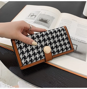 Gros plan du portefeuille en pied-de-poule avec bordure en cuir brun et boucle dorée