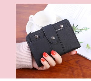 Close-up of black litchi grain leather wallet with metal rivets held in hand
