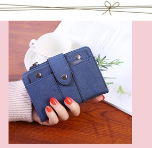 Detail of dark blue leather wallet featuring rivet buckle and smooth zipper closure