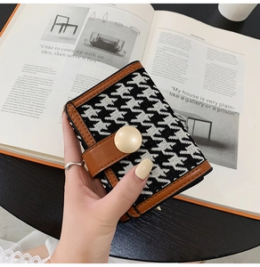 Gros plan du portefeuille pied-de-poule avec bordure en cuir brun et bouton vintage