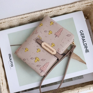 Detail shot of dusty pink wallet with mushroom pattern, wrist strap and gold metal closure
