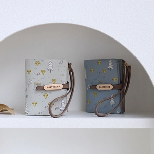 Close-up of forest-patterned short wallets with wristlet straps and snap closures