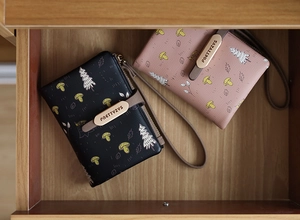 Flat lay of small PU leather wallets in black and pink with nature prints and wristlets