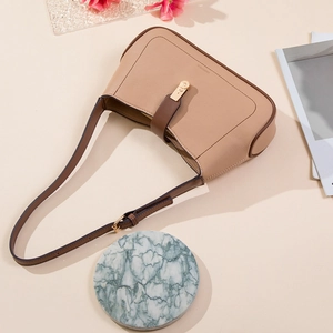 Beige underarm shoulder bag with brown trim and metal clasp on minimalist background