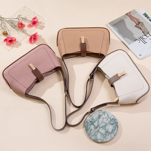 Close-up of minimalist leather underarm bags in three colors with metal buckle and pebble texture
