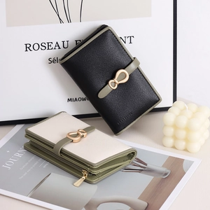 Detail of cross-grain leather wallets with golden bow clasp and avocado green edges