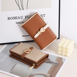 Close-up of litchi texture leather wallet with elegant metal bow clasp and zipper layers