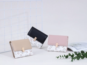 Close-up of three mini tri-fold wallets in black, pink and khaki with floral patterns