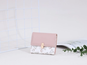 Detail of a floral trifold wallet with pink flap and golden engraved metal buckle