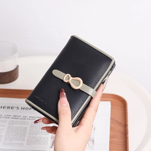 Close-up of black pebble leather wallet with olive green trim and golden bow buckle