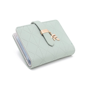 Detail of mint green quilted wallet with golden leaf pendant and multi-slot card holder