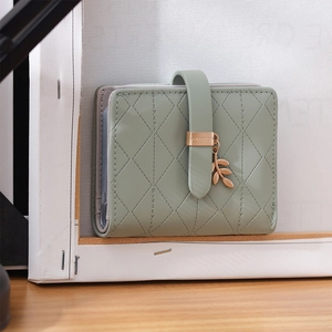Close-up of light green quilted RFID wallet featuring a gold leaf charm and buckle
