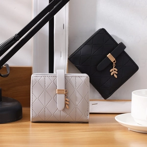 Detail of leaf-shaped metal pendant and quilted texture on two compact RFID wallets