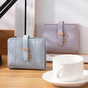 Close-up of quilted card wallets with leaf pendant and metal buckle in soft pastel colors